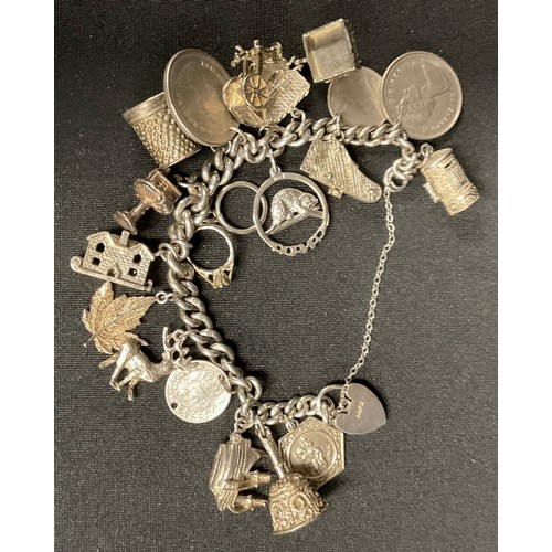 70 - A sterling silver albert chain charm bracelet, nineteen charms en suite, including a stag, coins, ma... 