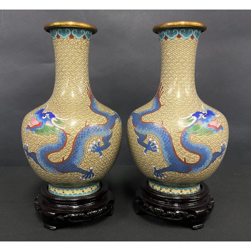 87 - A pair of Chinese cloisonne ovoid vases, decorated in polychrome enamels, with dragons, carved bases... 