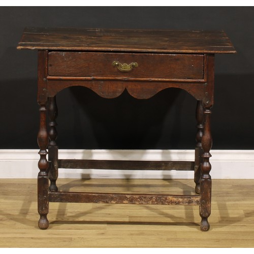 1569 - An early 18th century oak side table, oversailing rectangular top above a frieze drawer, shaped apro... 