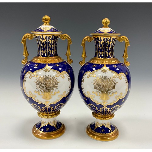 1337 - A pair of limited edition Royal Crown Derby vases and covers comprising a cobalt blue twin handled v... 