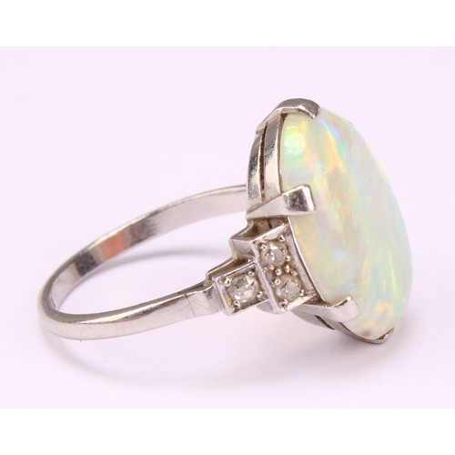 687 - An Art Deco platinum ring, the central large claw set polished opal cabochon, flanked to either side... 