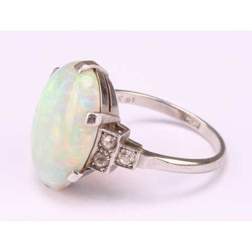 687 - An Art Deco platinum ring, the central large claw set polished opal cabochon, flanked to either side... 