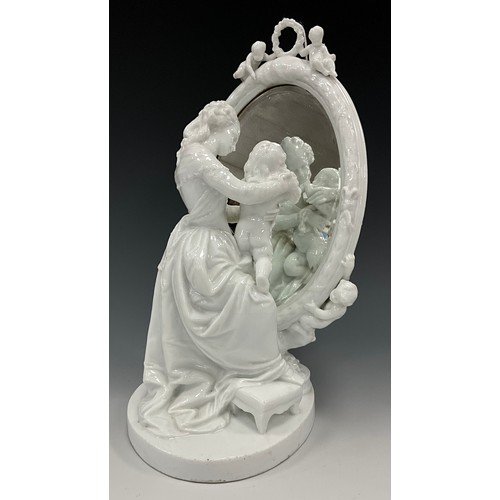 1347 - A continental porcelain blanc de chine figure of mother and child looking into an oval bevelled look... 