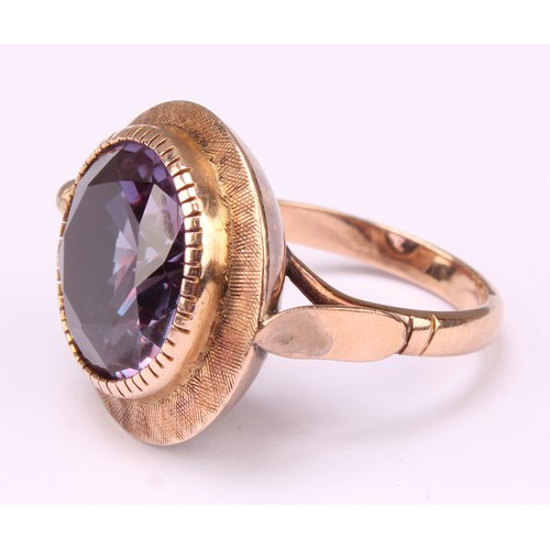 543 - A bespoke 14k rose gold ring, set slightly off centre with a large faceted amethyst, hand engraved b... 