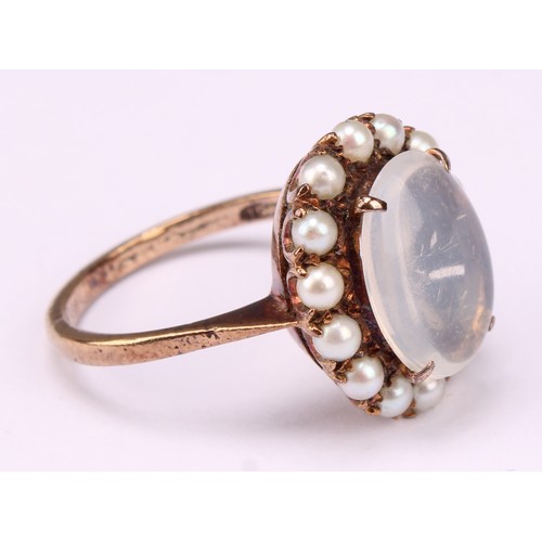 542 - A 9ct rose gold ring, set with a polished oval moonstone cabochon, surrounded by fourteen lustrous s... 