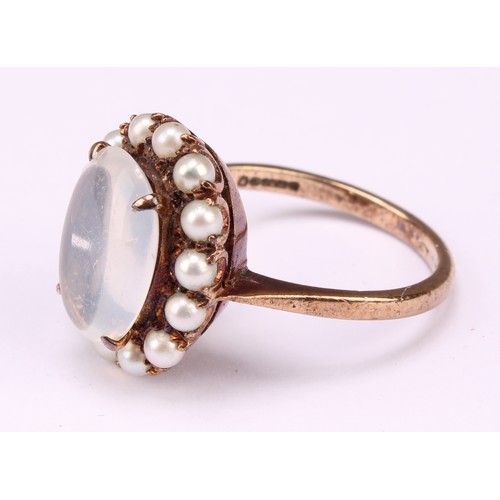 542 - A 9ct rose gold ring, set with a polished oval moonstone cabochon, surrounded by fourteen lustrous s... 