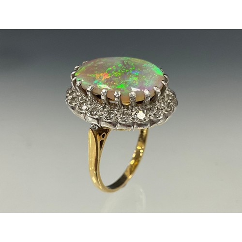 699 - An impressive opal and diamond cluster ring, large oval opal cabochon approx 17mm x 13mm flashing vi... 