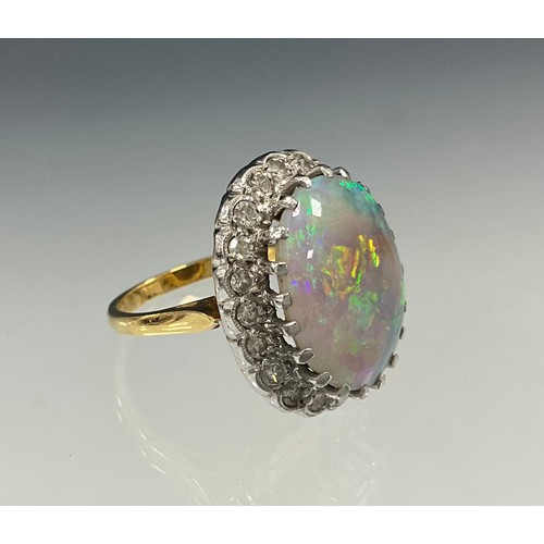 699 - An impressive opal and diamond cluster ring, large oval opal cabochon approx 17mm x 13mm flashing vi... 