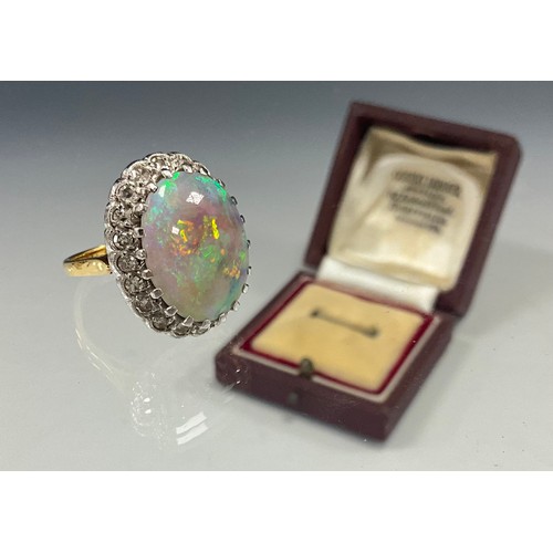 699 - An impressive opal and diamond cluster ring, large oval opal cabochon approx 17mm x 13mm flashing vi... 