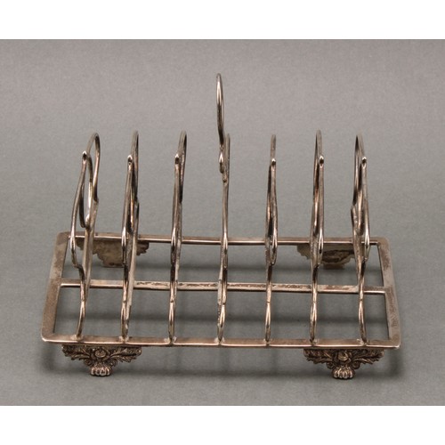 362 - A George IV silver seven bar toast rack, loop handle, whiplash divisions, acanthus, rose and paw fee... 