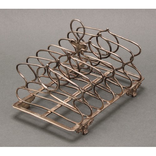 362 - A George IV silver seven bar toast rack, loop handle, whiplash divisions, acanthus, rose and paw fee... 