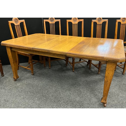 2143 - An Arts and Crafts oak dining suite, canted rectangular top, wind-out mechanism with two additional ... 