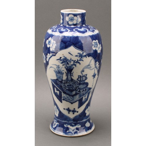 1385 - A Chinese baluster vase, painted in tones of underglaze blue with tables set with censers, planters ... 