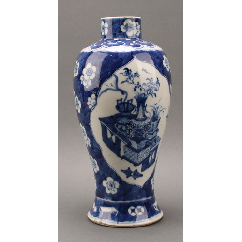 1385 - A Chinese baluster vase, painted in tones of underglaze blue with tables set with censers, planters ... 