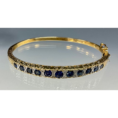 562 - A diamond and sapphire hinge bangle, alternate set with graduated blue sapphires and pairs of round ... 