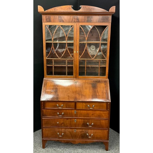 1911 - A Sheraton Revival mahogany bureau bookcase, shaped pediment above a pair of astral glazed doors enc... 