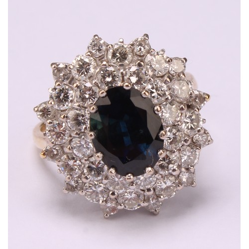 646 - A sapphire and diamond cluster ring, large oval mid blue green sapphire surrounded by three layers s... 