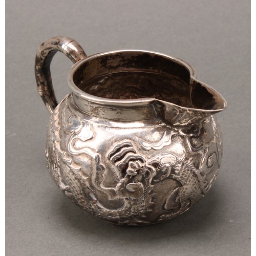 249 - A Chinese silver cream jug, chased with a dragon amongst scrolling clouds, faux, bamboo handle, 10cm... 