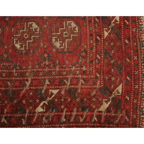 2065 - An Afghan rectangular woollen rug, the field with rows of geometric guls, 194cm x 124cm