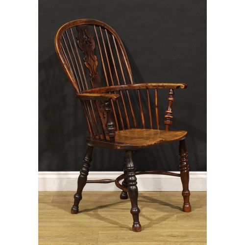 1677 - A 19th century yew and elm Windsor elbow chair, hoop back, unusual splat shaped and pierced with a h... 