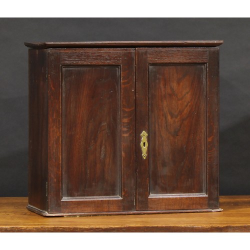 1674 - A 19th century oak table-top enclosed collector’s cabinet, oversailing top above a pair of panel doo... 