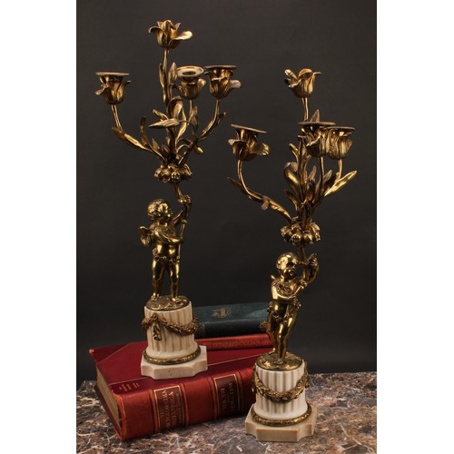 1845 - A pair of 19th century gilt metal candelabra, each cast as a scantily clad putto holding flowering b... 