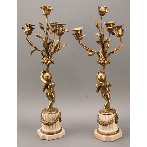 1845 - A pair of 19th century gilt metal candelabra, each cast as a scantily clad putto holding flowering b... 