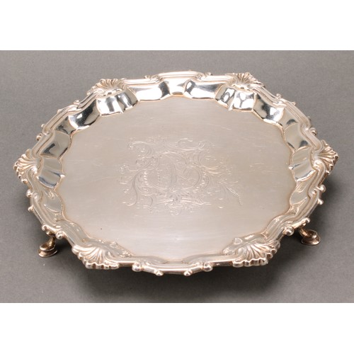 268 - A George II silver shaped circular salver, fluted shell and scroll border, armorial field, hoof feet... 