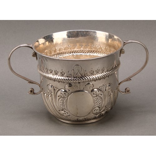 367 - A large Queen Anne silver porringer, wrythen-fluted below a chased rope-twist girdle, scroll handles... 