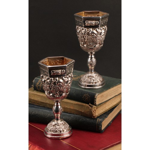 185 - Judaica - a pair of Jewish silver Kiddush cups, profuesly chased with fruiting vine, gilt interiors,... 