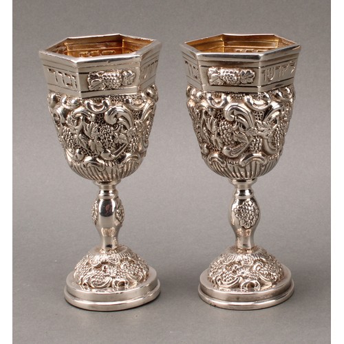 185 - Judaica - a pair of Jewish silver Kiddush cups, profuesly chased with fruiting vine, gilt interiors,... 