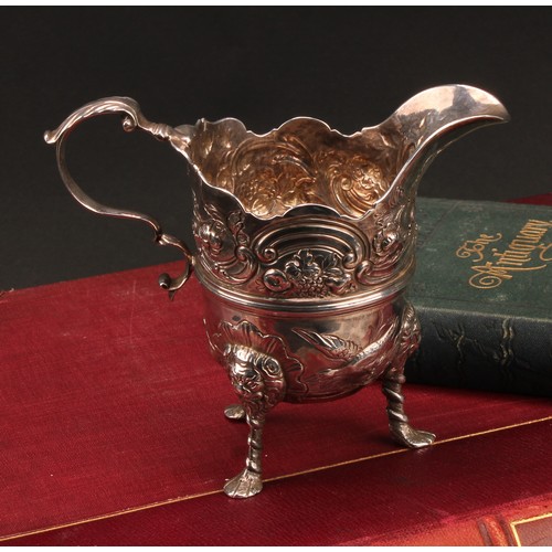 445 - An 18th century Irish silver cream jug, of bold design, chased with ducks taking to flight, flowers,... 