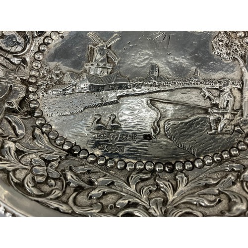 255 - A Dutch silver twin handled oval bowl, embossed with traditional landscape within scrolling border, ... 