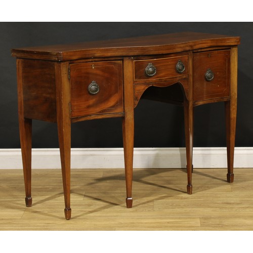 1685 - A George III Revival mahogany serpentine serving table, oversailing top outlined with barber pole st... 