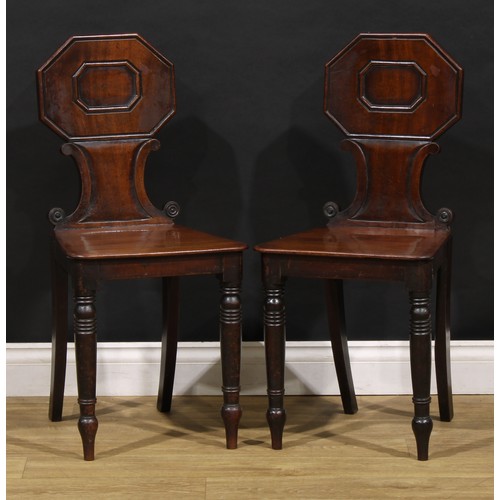 1610 - A pair of George/William IV mahogany hall chairs, each shaped back with octagonal cresting above C-s... 