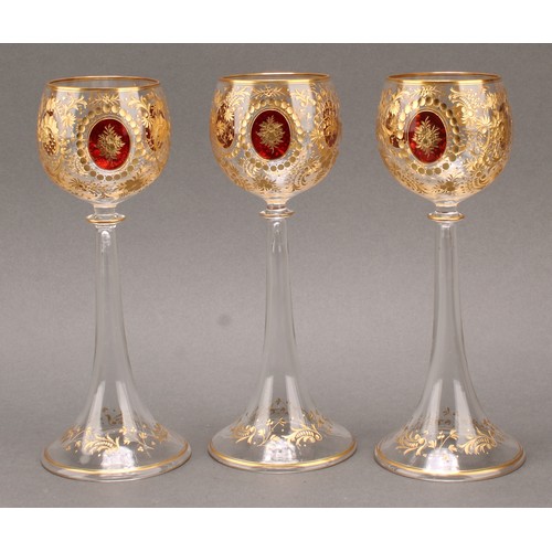 1372 - A set of three Bohemian etched and gilt harrach or wine glasses, the globular bowls with three oval ... 