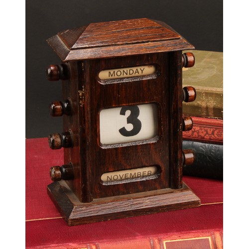 1886 - An early 20th century oak perpetual desk calendar, sarcophagus cresting above glazed apertures for d... 