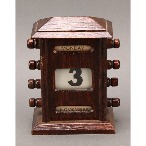 1886 - An early 20th century oak perpetual desk calendar, sarcophagus cresting above glazed apertures for d... 