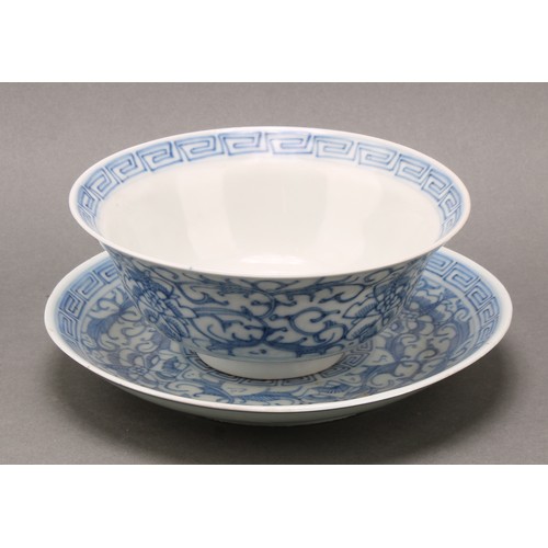 1402 - A Chinese klapmuts bowl and stand, painted in tones of underglaze blue with flowers and leafy scroll... 