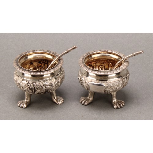 370 - A pair of Chinese silver cauldron salts, boldly cast with figures and pagodas amongst blossoming pru... 