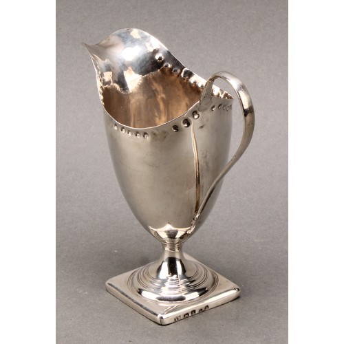 118 - A George III helmet shaped silver cream jug, punch beaded border, scroll handle, square base, 12.5cm... 