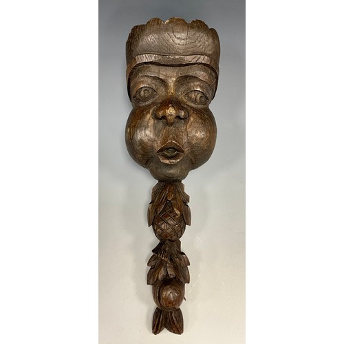 1803 - A 19th century oak boss or applique, carved as a mask above a fruiting foliate pendant, 30cm long