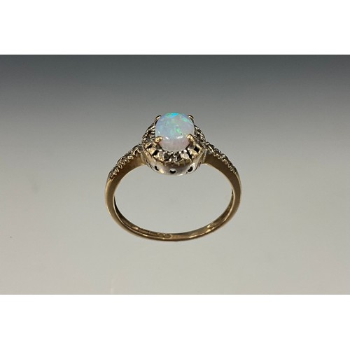 703 - An opal and diamond ring, oval cabochon opal flashing green, blue and orange play, with diamond acce... 