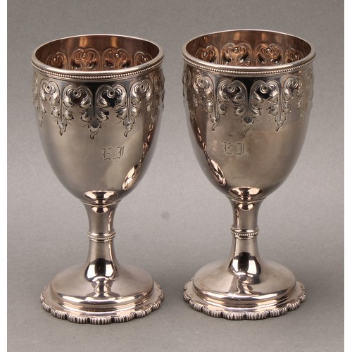 234 - Tiffany & Co - a pair of 19th century American silver pedestal goblets, chased in the Gothic taste w... 