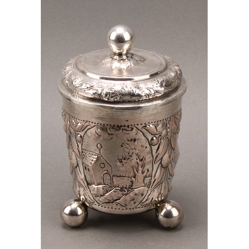 93 - A German silver beaker and cover, chased with a church and farm buildings, within cartouches on a gr... 