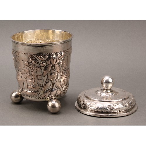 93 - A German silver beaker and cover, chased with a church and farm buildings, within cartouches on a gr... 