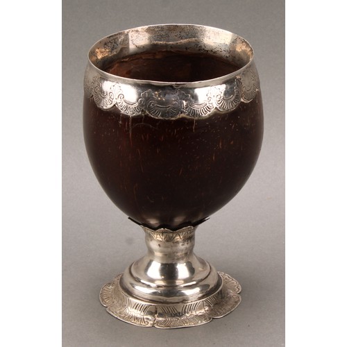 448 - An 18th century silver mounted pedestal coconut cup, ovoid bowl with wavy mount engraved with flower... 