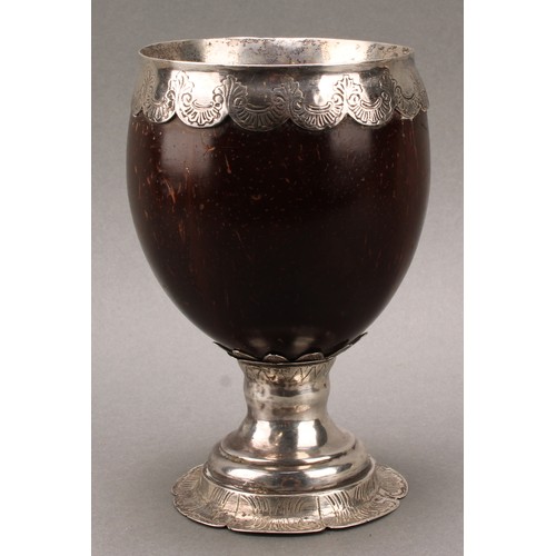 448 - An 18th century silver mounted pedestal coconut cup, ovoid bowl with wavy mount engraved with flower... 