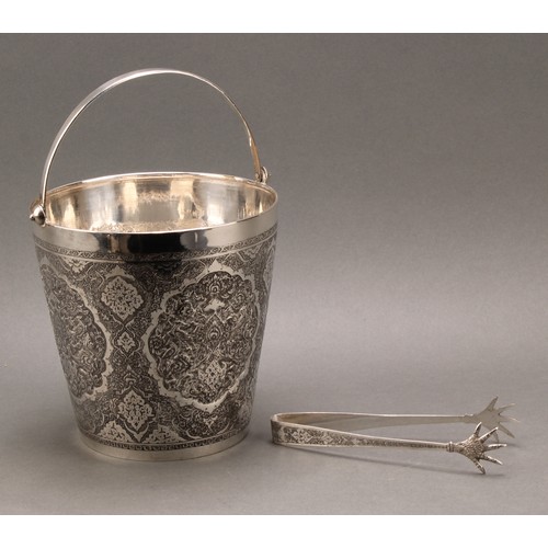 486 - An Iranian silver ice bucket, profusely chased in the Persian taste, tongs en suite, 18.5cm high exc... 