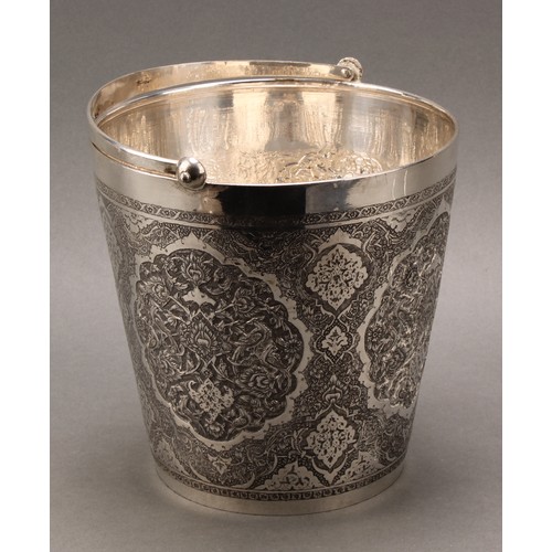 486 - An Iranian silver ice bucket, profusely chased in the Persian taste, tongs en suite, 18.5cm high exc... 